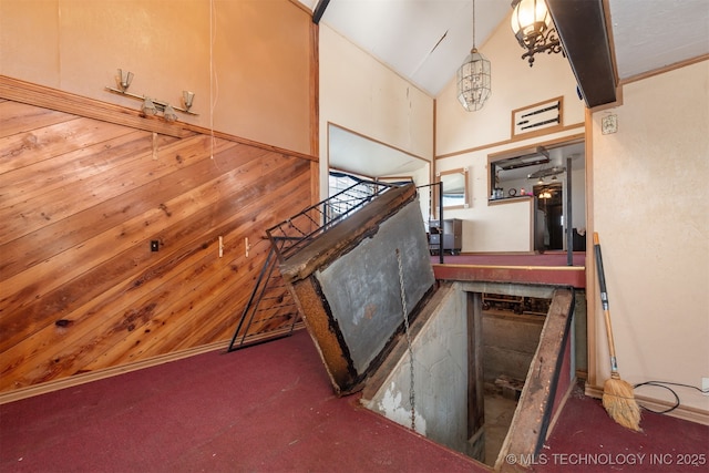 staircase with wood walls, carpet floors, and lofted ceiling