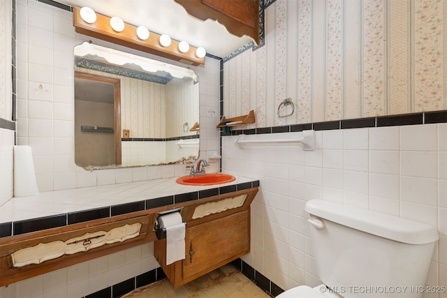 bathroom with tile walls, toilet, and vanity