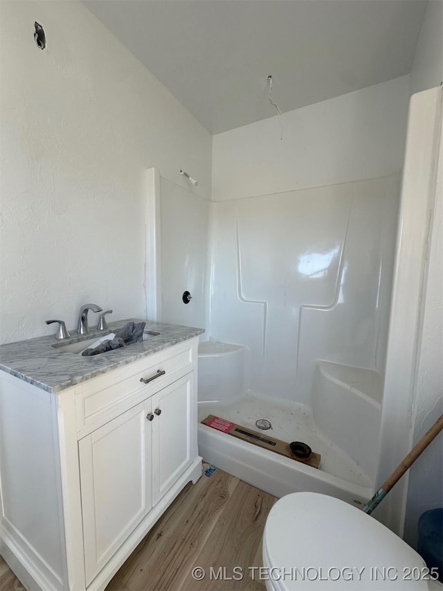 bathroom featuring wood-type flooring, toilet, walk in shower, and vanity