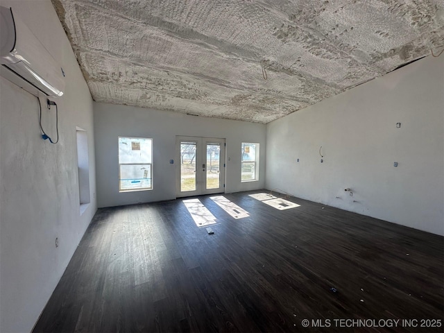 spare room featuring french doors, an AC wall unit, and hardwood / wood-style floors