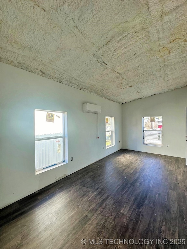 empty room with an AC wall unit and dark wood-type flooring