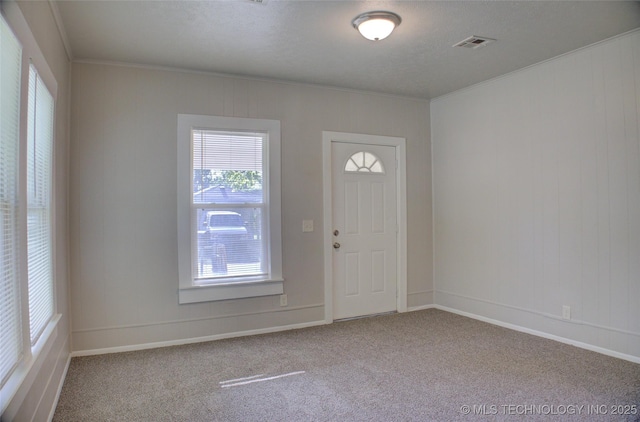 entrance foyer featuring crown molding and light colored carpet