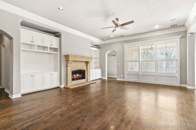 unfurnished living room with ceiling fan, dark wood-type flooring, built in features, and crown molding