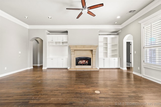 unfurnished living room featuring built in shelves, dark hardwood / wood-style floors, and crown molding