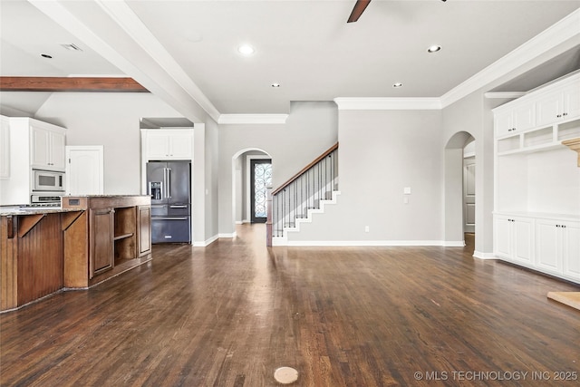 unfurnished living room featuring ceiling fan, dark wood-type flooring, beam ceiling, and ornamental molding