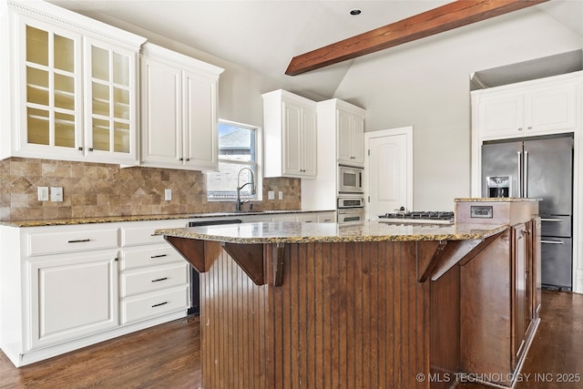 kitchen with stainless steel appliances, a kitchen island, dark stone countertops, and a kitchen breakfast bar