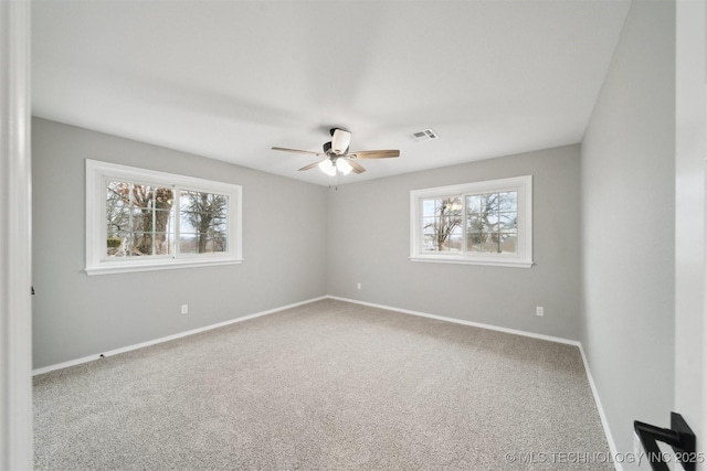 carpeted spare room featuring ceiling fan and plenty of natural light