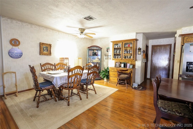 dining area with hardwood / wood-style flooring, a textured ceiling, and ceiling fan