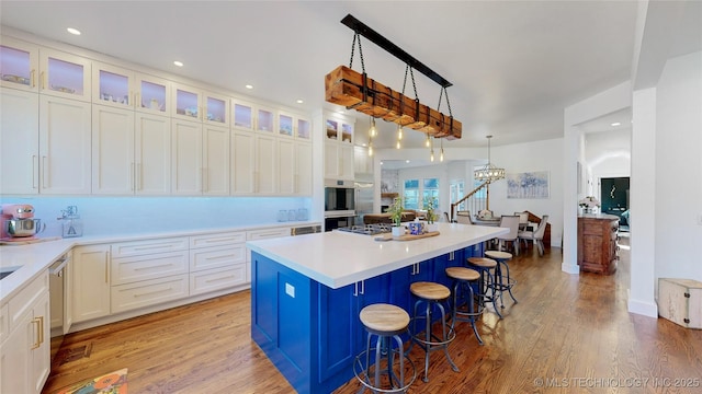 kitchen with a kitchen bar, decorative light fixtures, a kitchen island, light hardwood / wood-style floors, and white cabinets