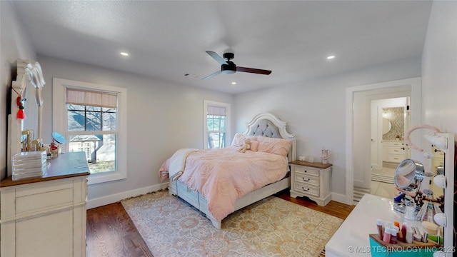 bedroom with multiple windows, ensuite bath, light hardwood / wood-style floors, and ceiling fan