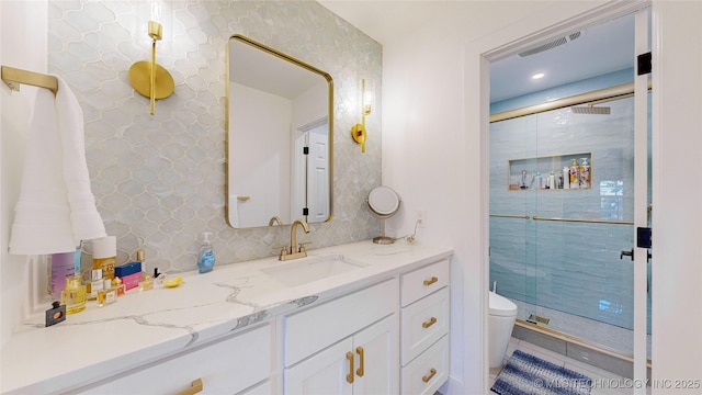 bathroom with tasteful backsplash, vanity, toilet, and a shower with shower door