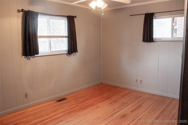 empty room featuring crown molding, plenty of natural light, and light wood-type flooring