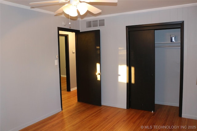 unfurnished bedroom featuring wood-type flooring, ornamental molding, a closet, and ceiling fan