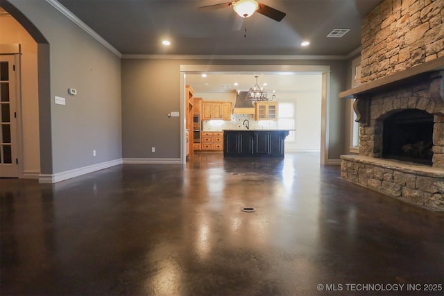 unfurnished living room with ceiling fan, ornamental molding, and a stone fireplace