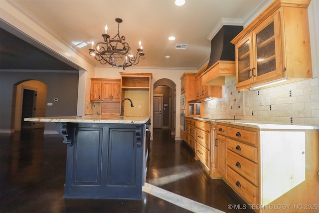 kitchen with a breakfast bar, hanging light fixtures, light stone counters, a center island with sink, and decorative backsplash