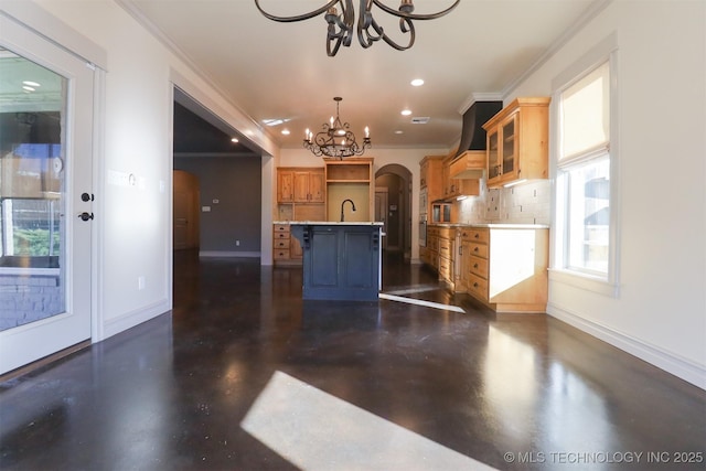 kitchen featuring premium range hood, an inviting chandelier, a center island with sink, ornamental molding, and a kitchen bar