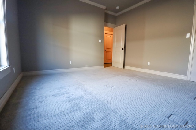 empty room featuring crown molding and carpet