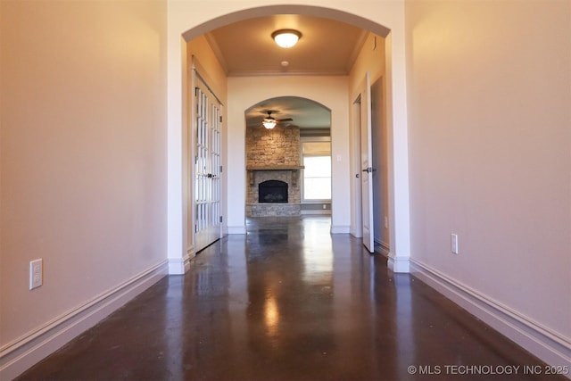 unfurnished living room with ornamental molding and a stone fireplace