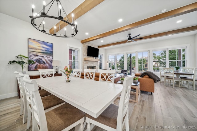 dining area with a fireplace, beam ceiling, and ceiling fan with notable chandelier