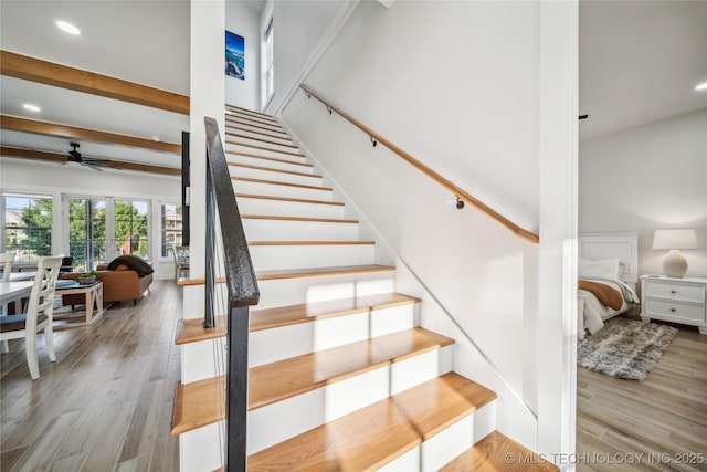 stairway featuring ceiling fan, hardwood / wood-style flooring, and beamed ceiling