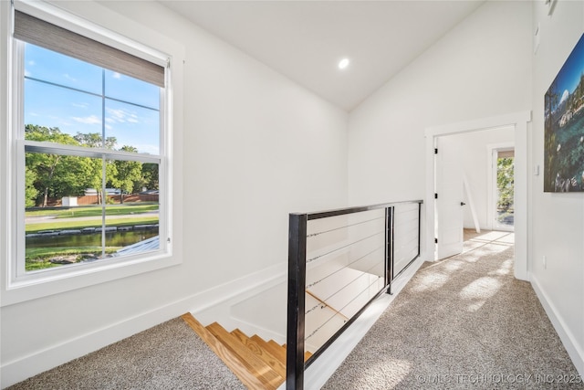 hallway featuring vaulted ceiling, a water view, and light carpet