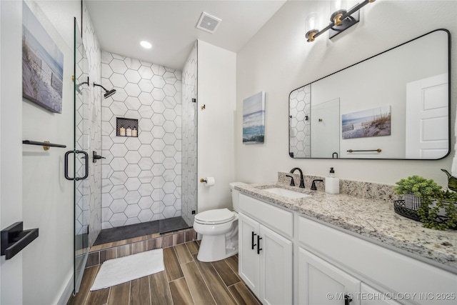 bathroom featuring vanity, toilet, and a shower with door