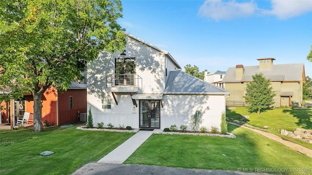 view of front of home featuring a front lawn, a balcony, and central air condition unit