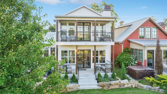 back of property with a hot tub, a patio, and a balcony