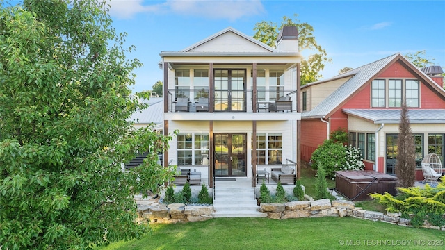 back of property featuring a yard, a hot tub, a patio, and a balcony