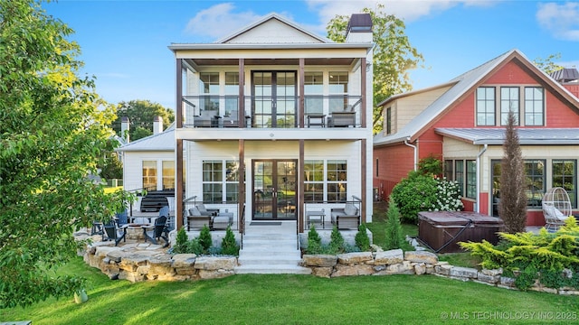 back of property with a hot tub, a patio, a balcony, and a yard