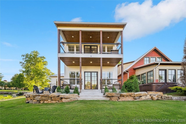 rear view of house featuring a hot tub, a balcony, a yard, and french doors