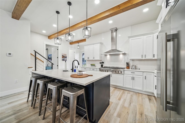 kitchen with a kitchen island with sink, beam ceiling, stainless steel appliances, ventilation hood, and white cabinets