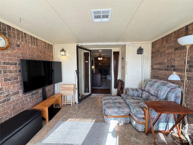 living room featuring ceiling fan, a fireplace, ornamental molding, and a textured ceiling