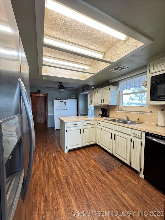 kitchen featuring sink, black appliances, washing machine and clothes dryer, dark hardwood / wood-style flooring, and kitchen peninsula