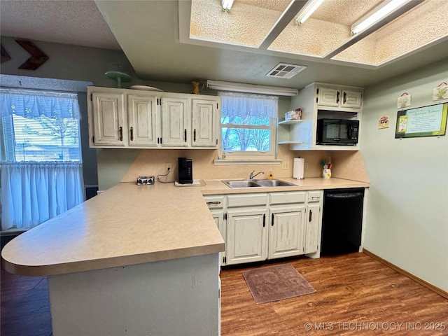 kitchen with dark hardwood / wood-style floors, black appliances, kitchen peninsula, and white cabinets