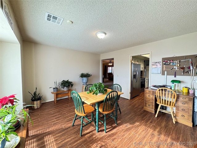 dining space featuring dark hardwood / wood-style flooring and a textured ceiling