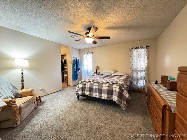 bedroom with carpet, a spacious closet, ceiling fan, a textured ceiling, and a closet