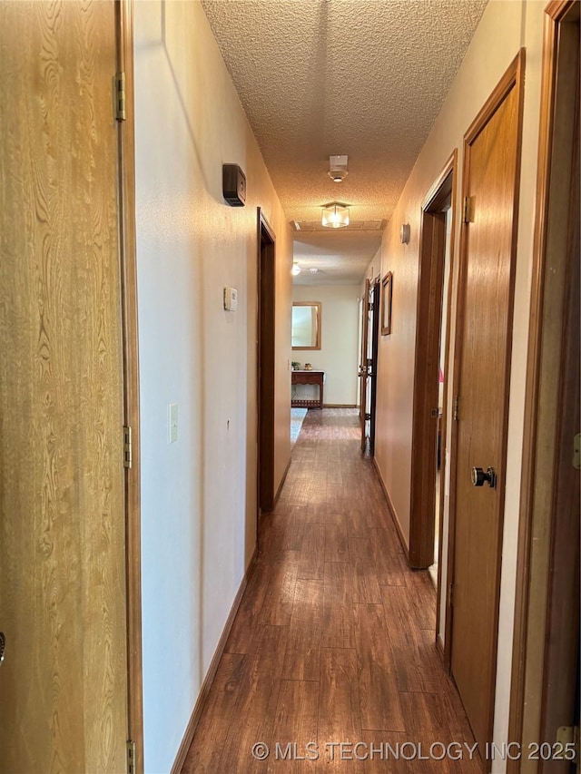 hallway with dark wood-type flooring and a textured ceiling