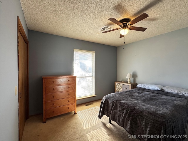 carpeted bedroom featuring ceiling fan and a textured ceiling