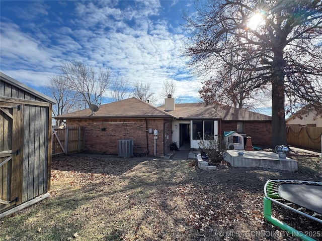 back of property featuring a trampoline, central AC unit, a storage shed, and a patio area