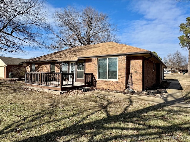 rear view of property with a wooden deck and a yard