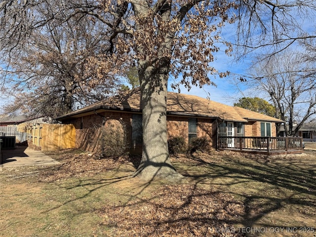 rear view of house featuring cooling unit, a deck, and a lawn