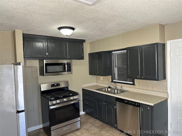 kitchen featuring appliances with stainless steel finishes, sink, backsplash, and a textured ceiling