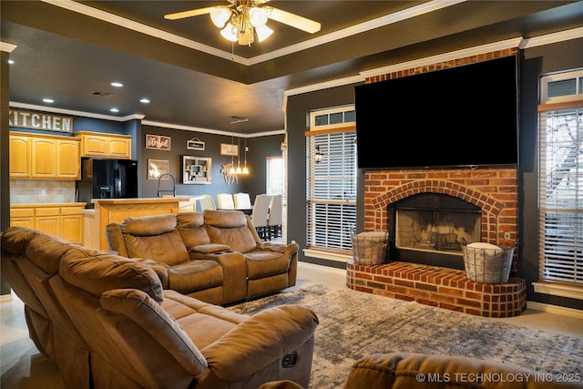 living room featuring crown molding, ceiling fan, a healthy amount of sunlight, and a brick fireplace