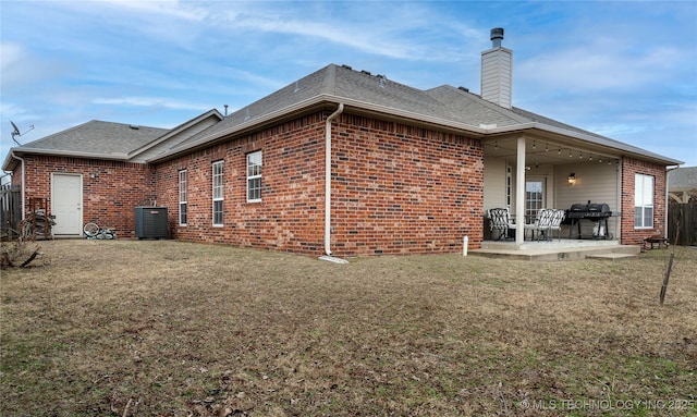 rear view of property with cooling unit, a patio area, and a lawn