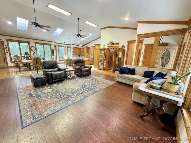 living room with ceiling fan, ornamental molding, wood-type flooring, and vaulted ceiling with skylight