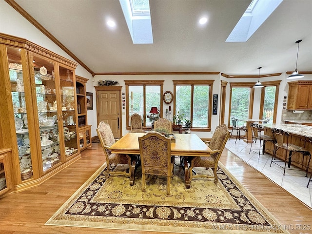 dining area with light hardwood / wood-style flooring, a wealth of natural light, and a skylight