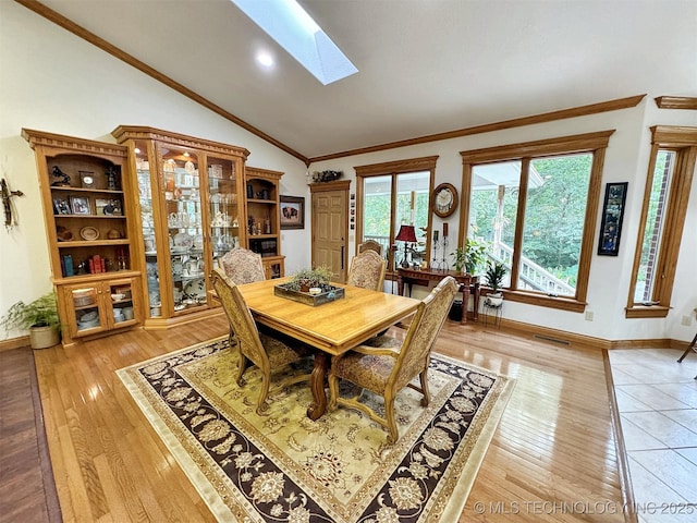 dining room featuring lofted ceiling with skylight, crown molding, and light hardwood / wood-style flooring