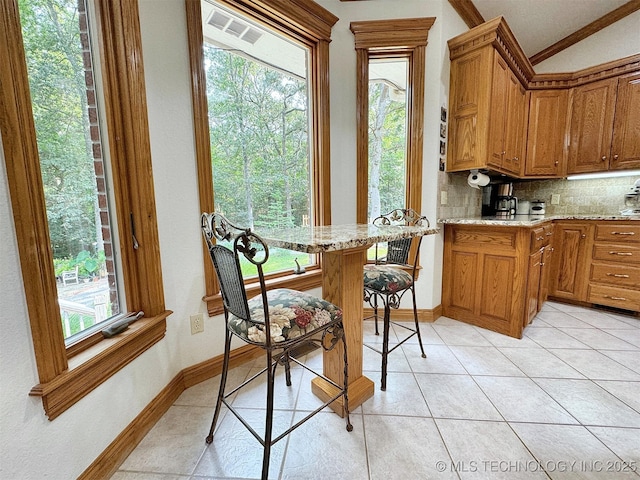 kitchen featuring a wealth of natural light, ornamental molding, kitchen peninsula, and decorative backsplash