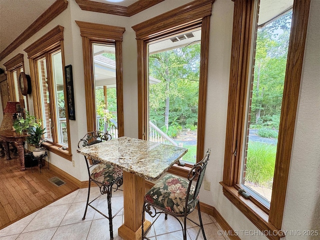 tiled dining space featuring crown molding and a healthy amount of sunlight